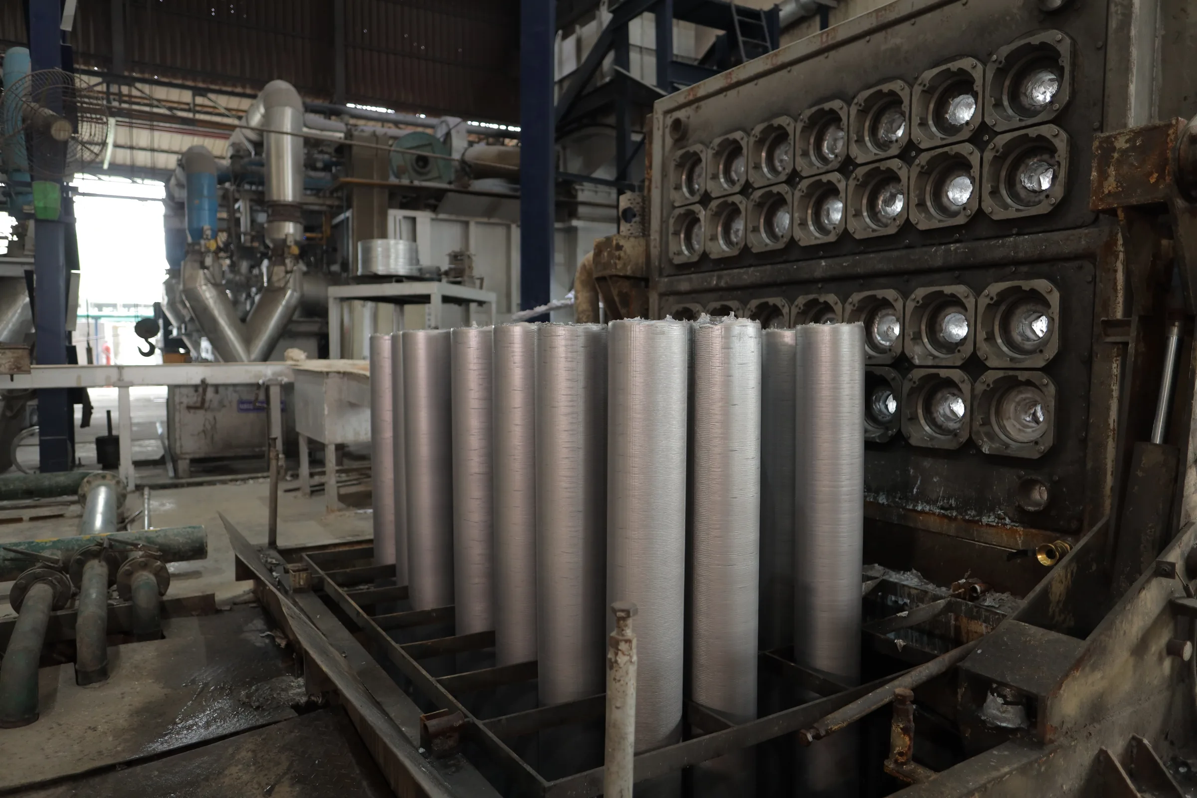 Freshly cast billets being lifted from the Hot-Top casting table at Banco Aluminium